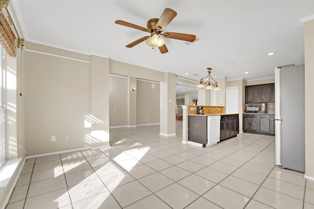 kitchen featuring dark brown cabinets, light tile patterned floors, ornamental molding, and white refrigerator