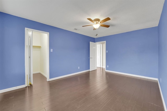 unfurnished room featuring a textured ceiling, dark hardwood / wood-style flooring, and ceiling fan