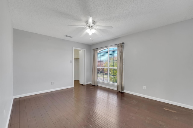 empty room with a textured ceiling, ceiling fan, and dark hardwood / wood-style floors