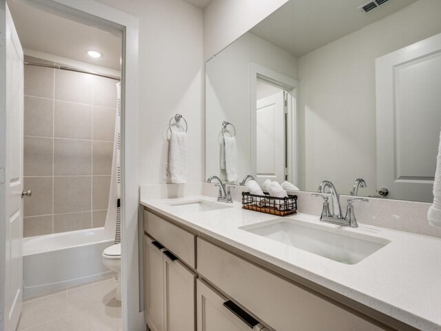 full bathroom featuring tile patterned flooring, vanity, tiled shower / bath, and toilet