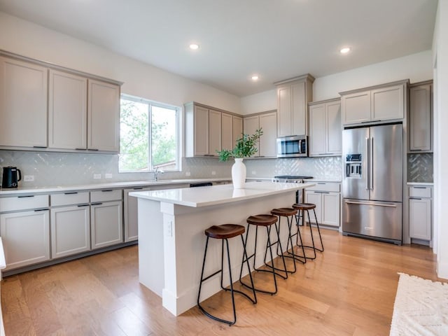 kitchen featuring stainless steel appliances, a kitchen breakfast bar, a center island, and gray cabinets