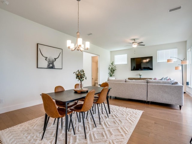 dining space featuring ceiling fan with notable chandelier and light hardwood / wood-style floors