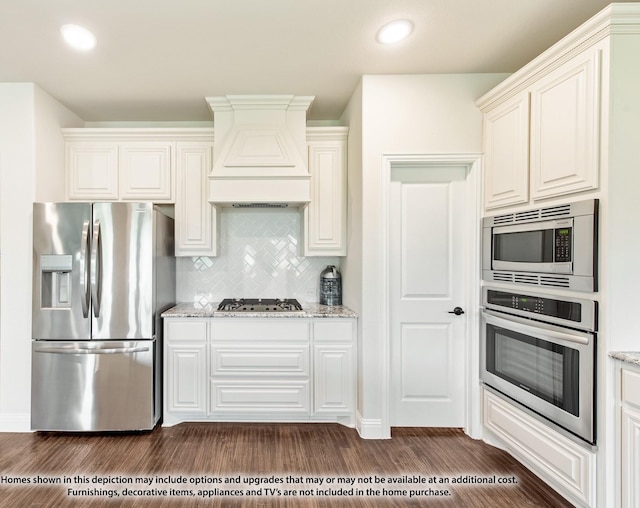 kitchen with dark hardwood / wood-style floors, light stone counters, premium range hood, and stainless steel appliances