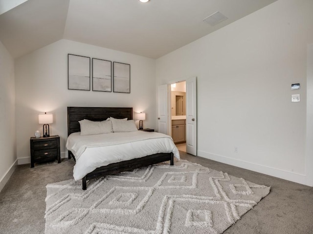 bedroom with ensuite bathroom, light colored carpet, and vaulted ceiling