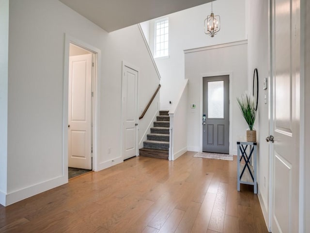 foyer with a towering ceiling, hardwood / wood-style floors, and a notable chandelier