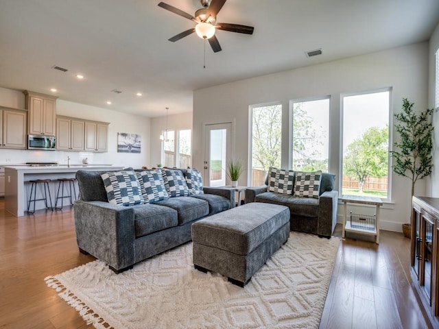 living room with light hardwood / wood-style floors, ceiling fan, and a healthy amount of sunlight