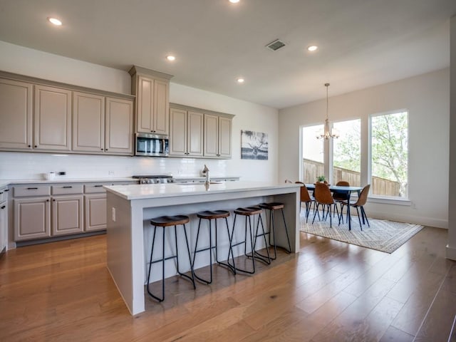 kitchen featuring a chandelier, light hardwood / wood-style floors, hanging light fixtures, and an island with sink