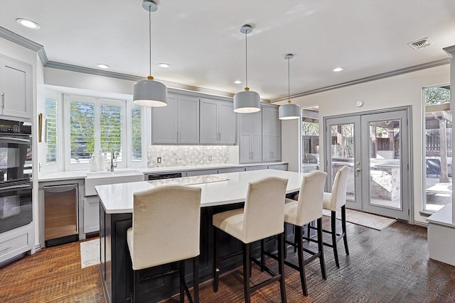 kitchen with sink, decorative light fixtures, a center island, gray cabinets, and black double oven