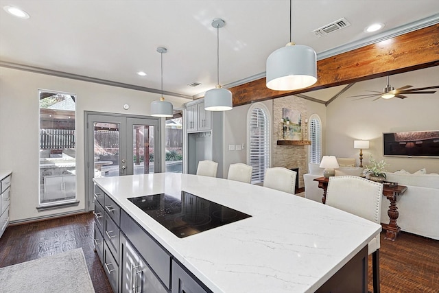 kitchen featuring black electric stovetop, decorative light fixtures, gray cabinets, and a kitchen bar