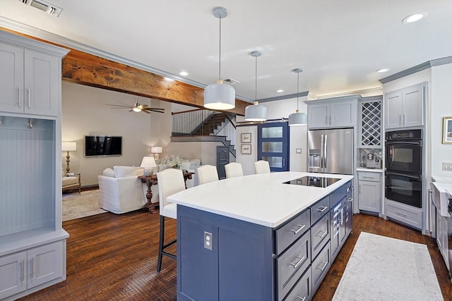 kitchen with a breakfast bar, hanging light fixtures, a center island, black appliances, and dark wood-type flooring