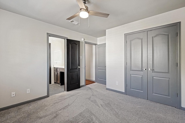 unfurnished bedroom with ceiling fan, a closet, carpet, and ensuite bathroom