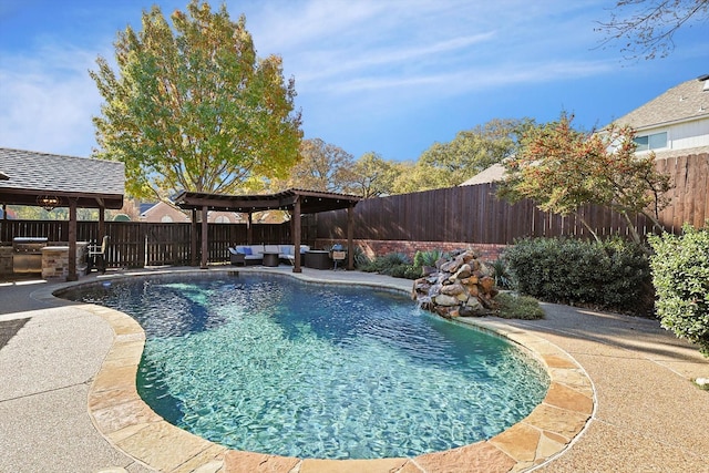 view of swimming pool with a patio, pool water feature, a pergola, and exterior kitchen