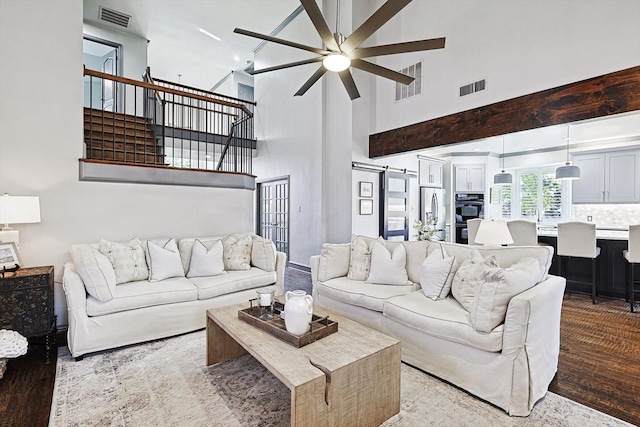 living room with ceiling fan, a barn door, and light wood-type flooring