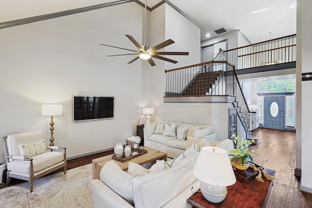 living room with ceiling fan, a towering ceiling, and wood-type flooring