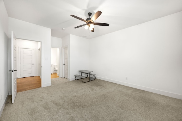 unfurnished bedroom featuring ceiling fan, light colored carpet, and ensuite bath