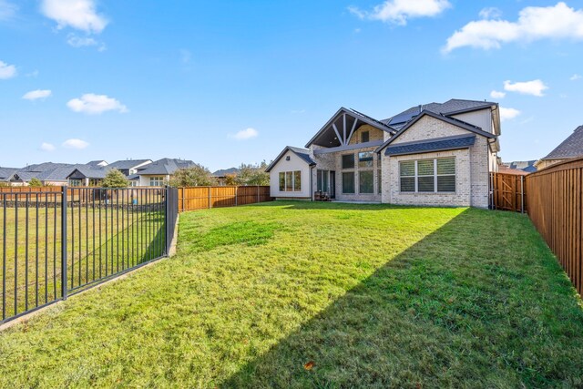 back of property featuring solar panels and a lawn