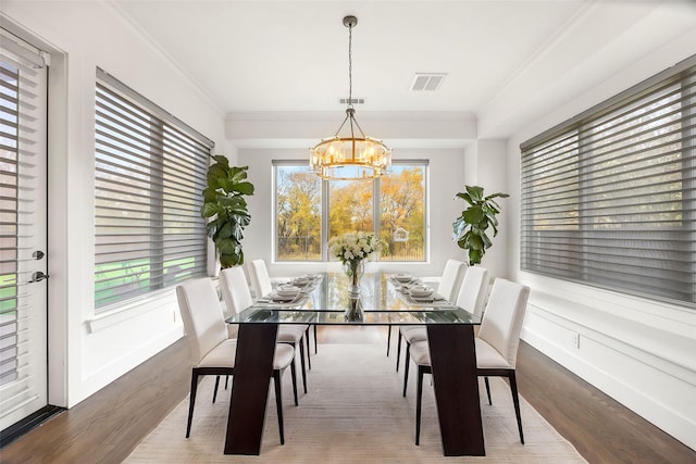 dining space featuring ornamental molding, a notable chandelier, and hardwood / wood-style flooring