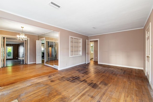 unfurnished room with hardwood / wood-style flooring, ornamental molding, and a chandelier