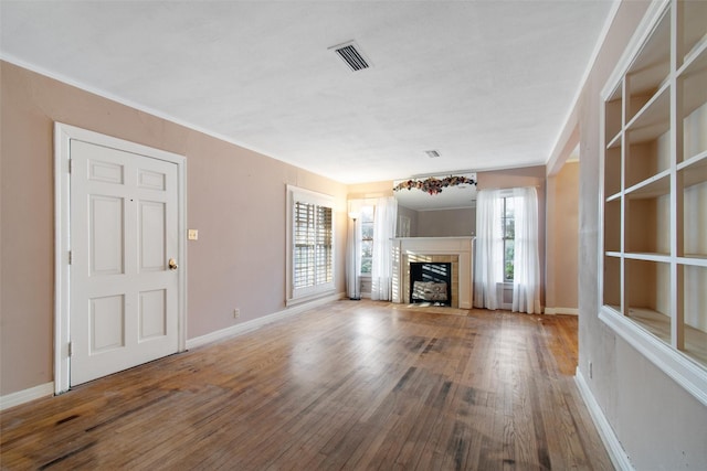 unfurnished living room featuring a fireplace with flush hearth, baseboards, visible vents, and hardwood / wood-style floors