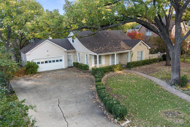 view of front of house with fence, driveway, a front lawn, stone siding, and a garage