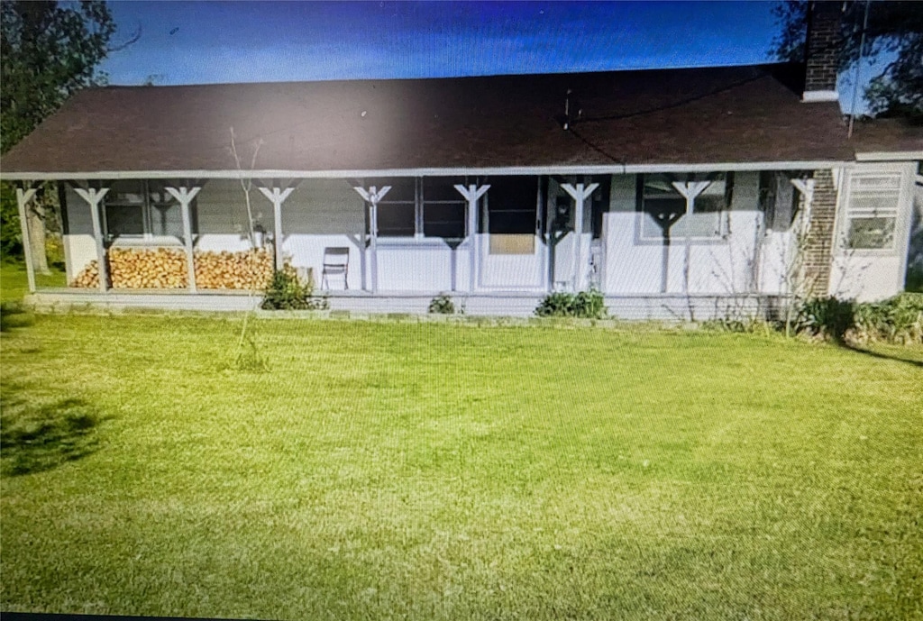 back of house featuring covered porch and a lawn