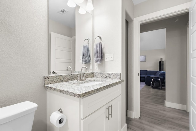 bathroom featuring hardwood / wood-style flooring, vanity, and toilet