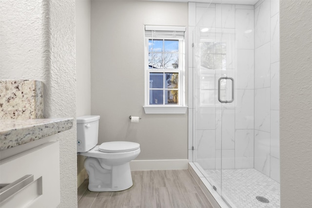 bathroom with wood-type flooring, toilet, and a shower with shower door