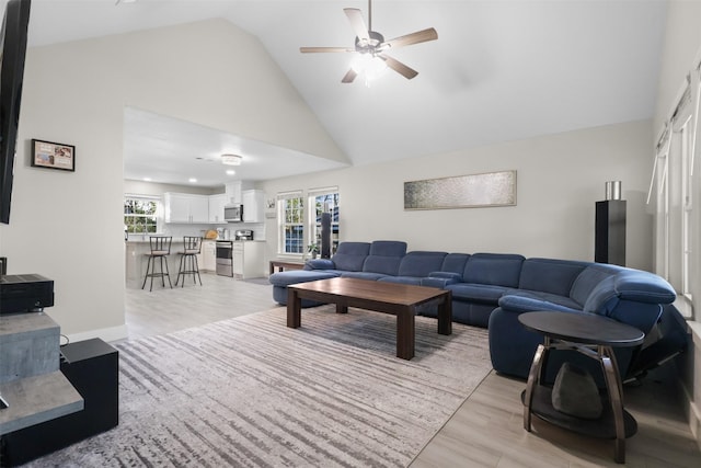 living room featuring high vaulted ceiling, ceiling fan, and light wood-type flooring