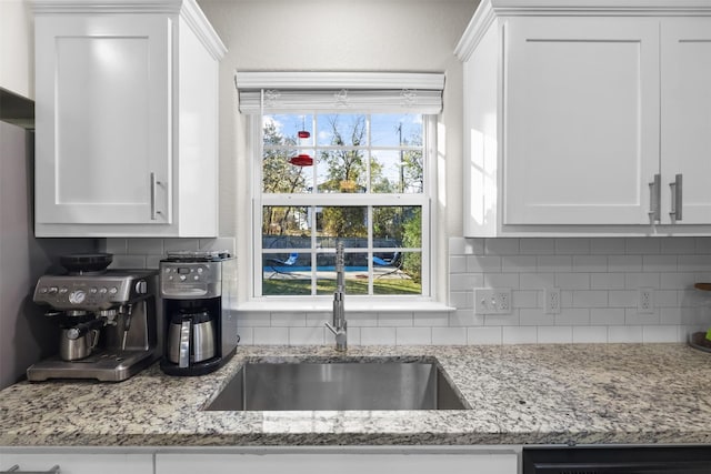 kitchen with sink, white cabinets, and backsplash