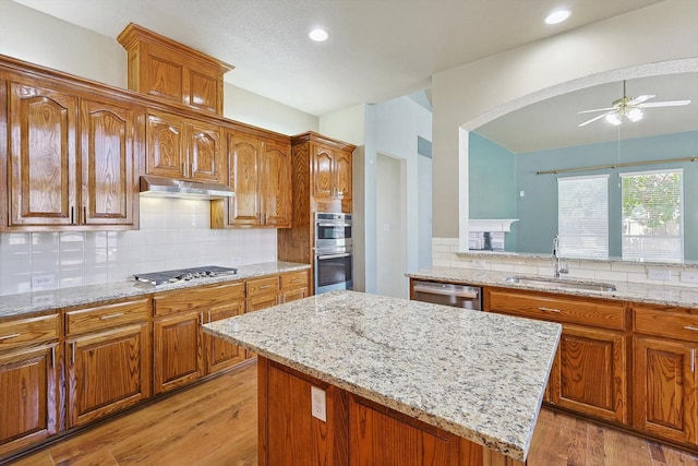 kitchen with sink, ceiling fan, light hardwood / wood-style floors, a kitchen island, and stainless steel appliances