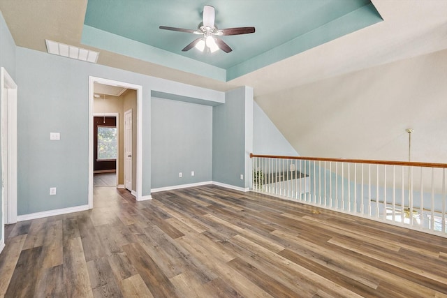 spare room featuring wood-type flooring, a tray ceiling, and ceiling fan