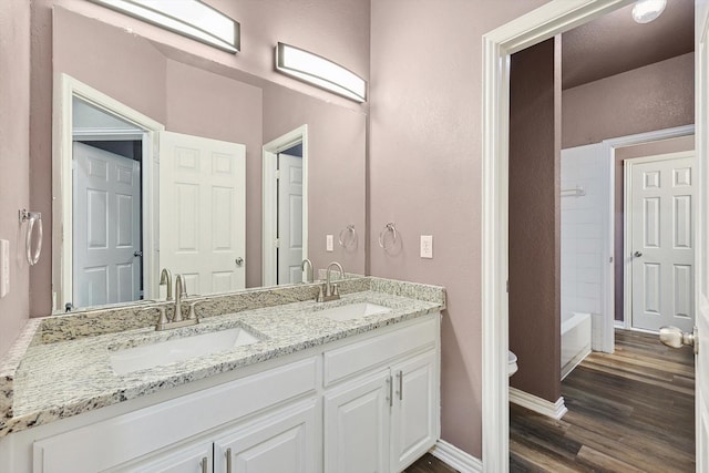 full bathroom with hardwood / wood-style flooring, vanity,  shower combination, and toilet