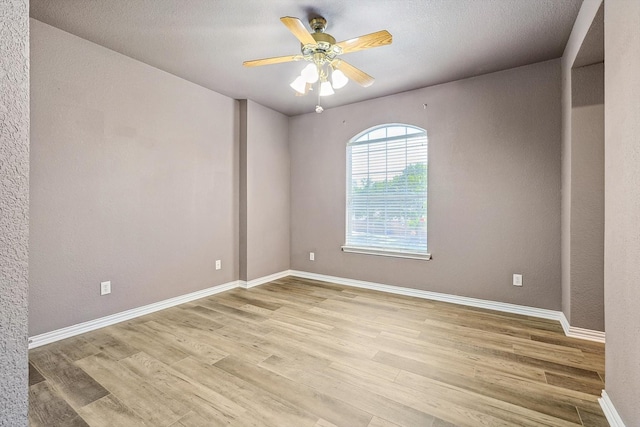 unfurnished room with a textured ceiling, light wood-type flooring, and ceiling fan