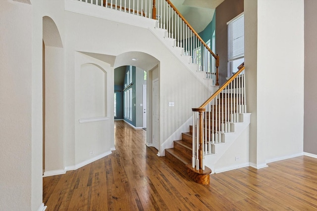 stairs featuring wood-type flooring and a high ceiling