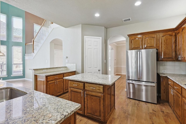 kitchen featuring stainless steel fridge, light hardwood / wood-style floors, a kitchen island, and a wealth of natural light