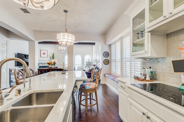 kitchen featuring sink, tasteful backsplash, dark hardwood / wood-style flooring, decorative light fixtures, and white cabinets