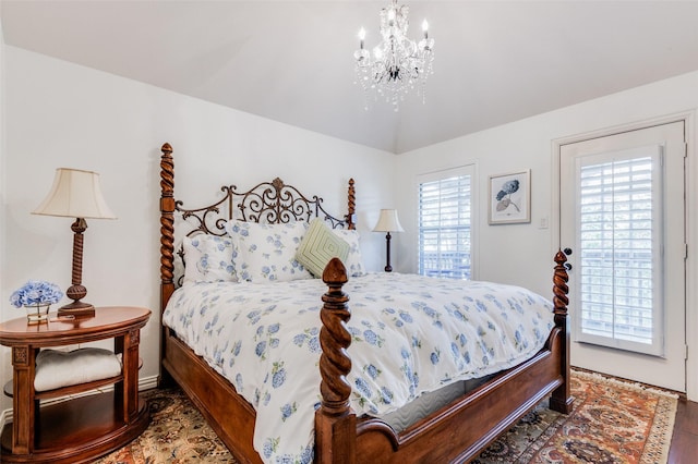 bedroom featuring access to outside, a chandelier, and wood-type flooring