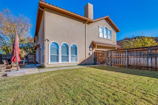 back of house with a lawn and a patio