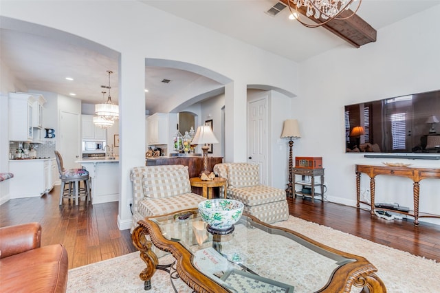 living room with sink, dark wood-type flooring, and an inviting chandelier