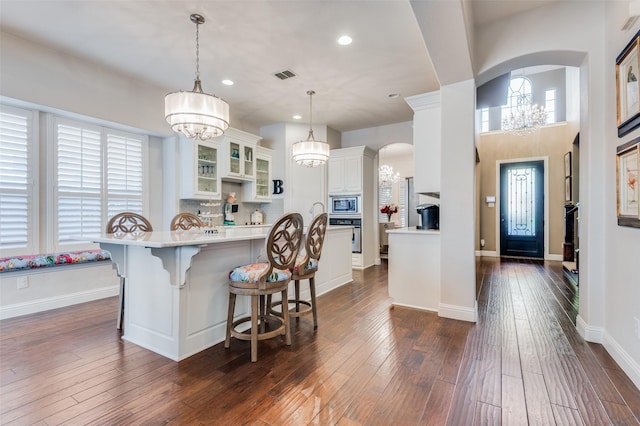 kitchen featuring decorative light fixtures, a kitchen breakfast bar, dark wood-type flooring, and appliances with stainless steel finishes