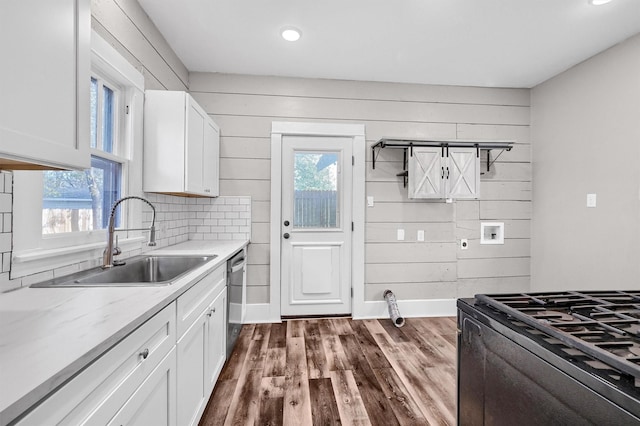 kitchen featuring dark hardwood / wood-style flooring, a wealth of natural light, wooden walls, sink, and white cabinetry