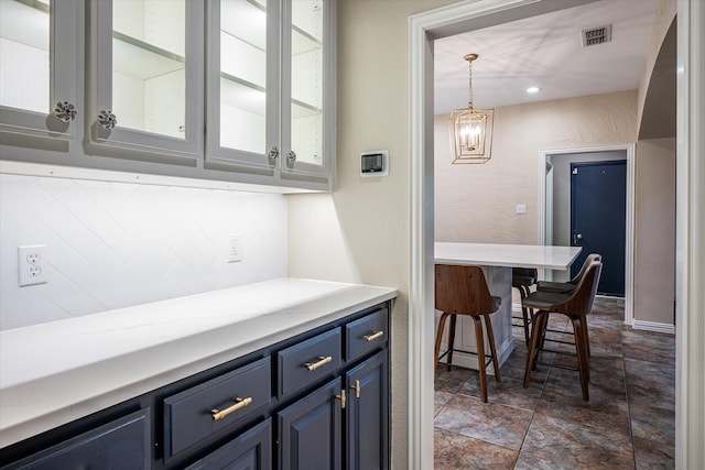 bar with hanging light fixtures, an inviting chandelier, and blue cabinetry