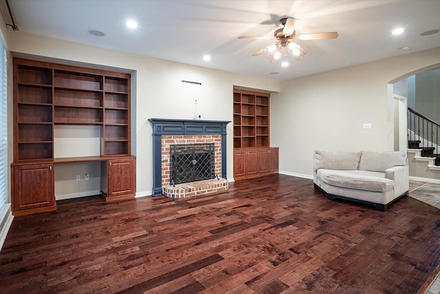 living room featuring ceiling fan, dark wood-type flooring, built in features, and a fireplace