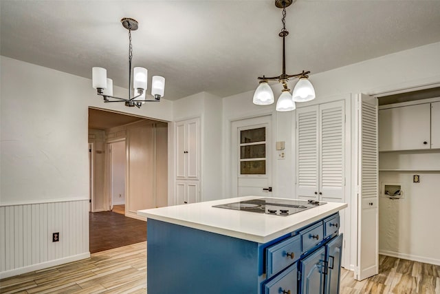 kitchen featuring blue cabinetry, hanging light fixtures, light hardwood / wood-style flooring, a notable chandelier, and electric cooktop