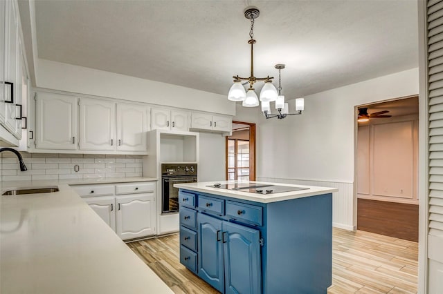 kitchen with blue cabinetry, sink, oven, pendant lighting, and white cabinets