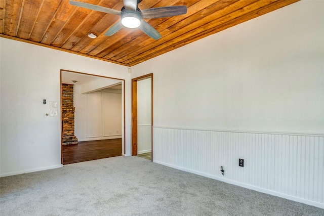 carpeted spare room with lofted ceiling, ceiling fan, wooden walls, and wood ceiling