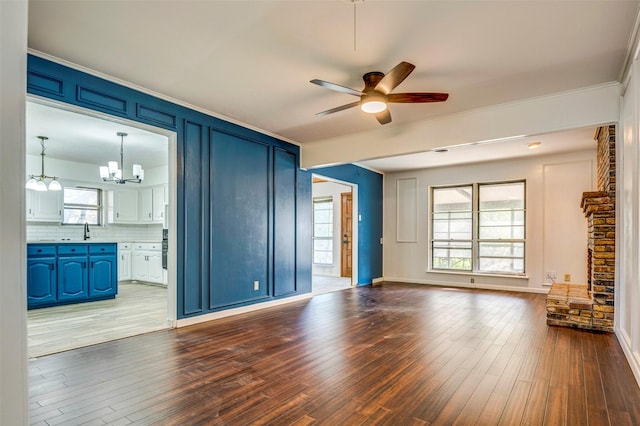 unfurnished living room with ceiling fan with notable chandelier, hardwood / wood-style flooring, and ornamental molding