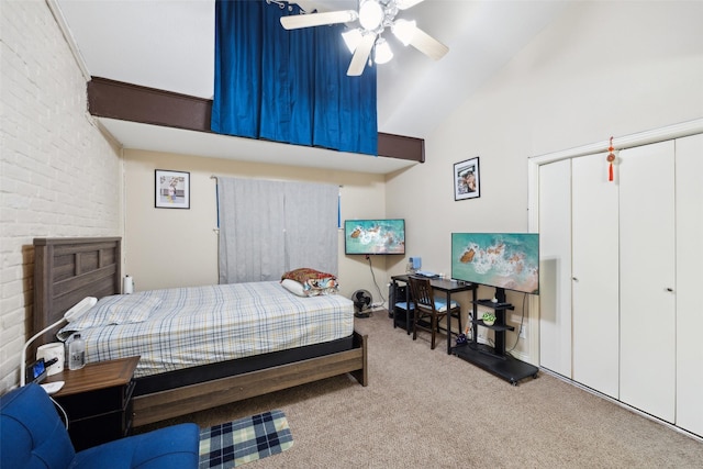 carpeted bedroom with high vaulted ceiling, ceiling fan, brick wall, and a closet