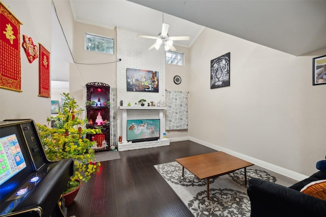 living room featuring high vaulted ceiling, hardwood / wood-style flooring, ceiling fan, ornamental molding, and a fireplace