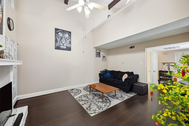 living room with a fireplace, ceiling fan, dark wood-type flooring, and a high ceiling